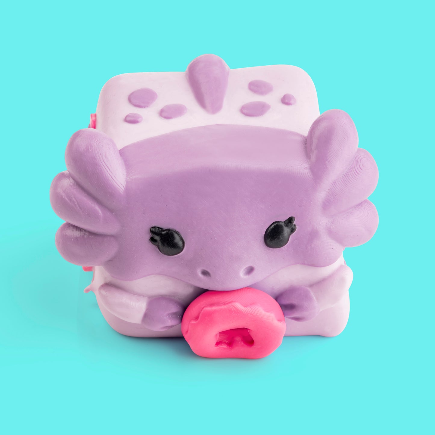 Mochi the Axolotl Mushykinz taba squishy top front view on a teal background holding a pink donut
