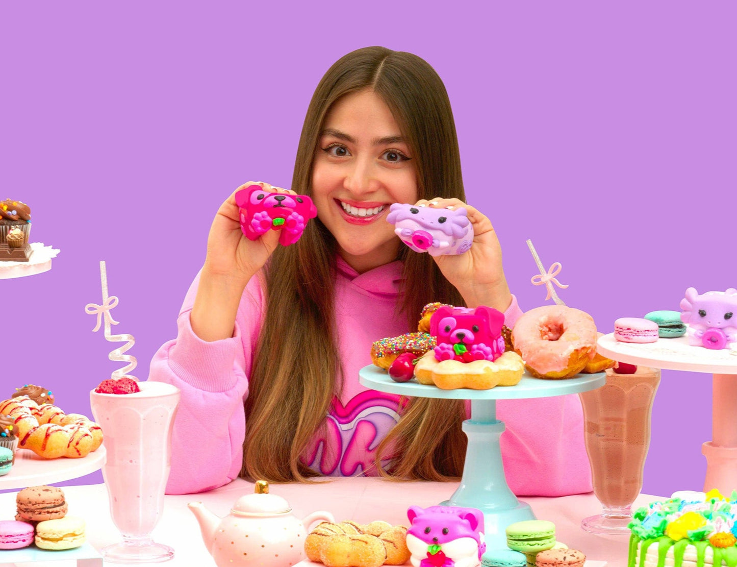 Anna showing her Mushykinz taba squishies with donuts in a colorful setting with pastries and desserts.