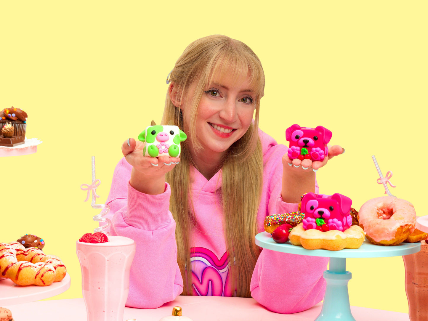 Erin showing her Mushykinz taba squishies in a pink outfit with colorful food and desserts on a yellow background