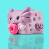 Mochi the Axolotl Mushykinz taba squishy left side view on a teal background holding a pink donut