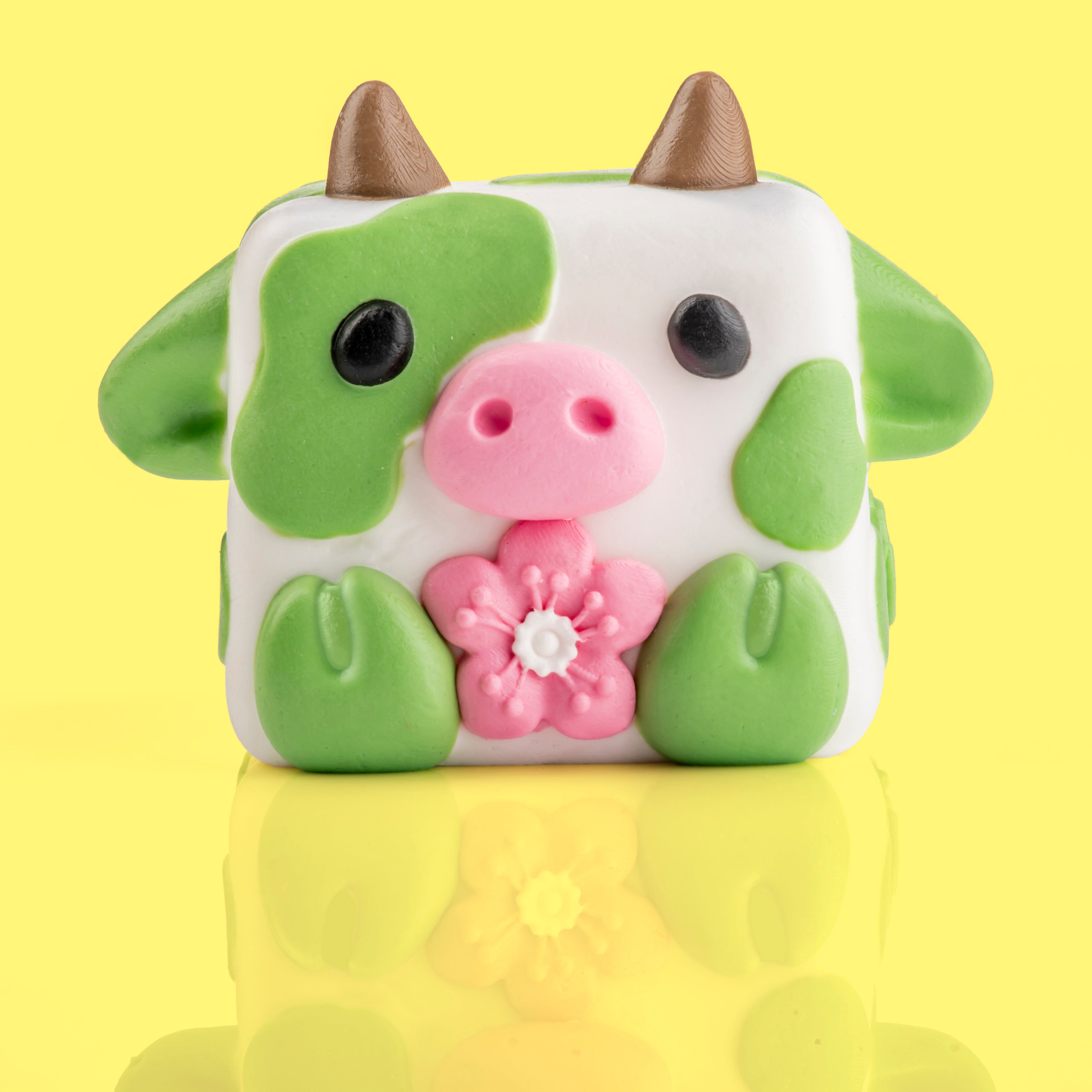 Chip the cow Mushykinz taba squishy front view on a yellow background holding a pink flower